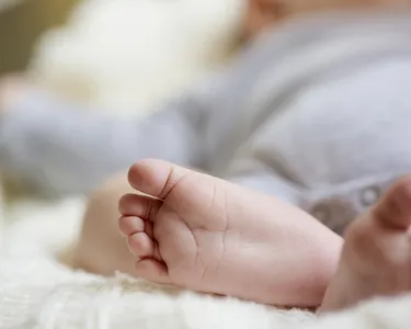 Close-up of a baby's feet as they lie down on a soft surface.